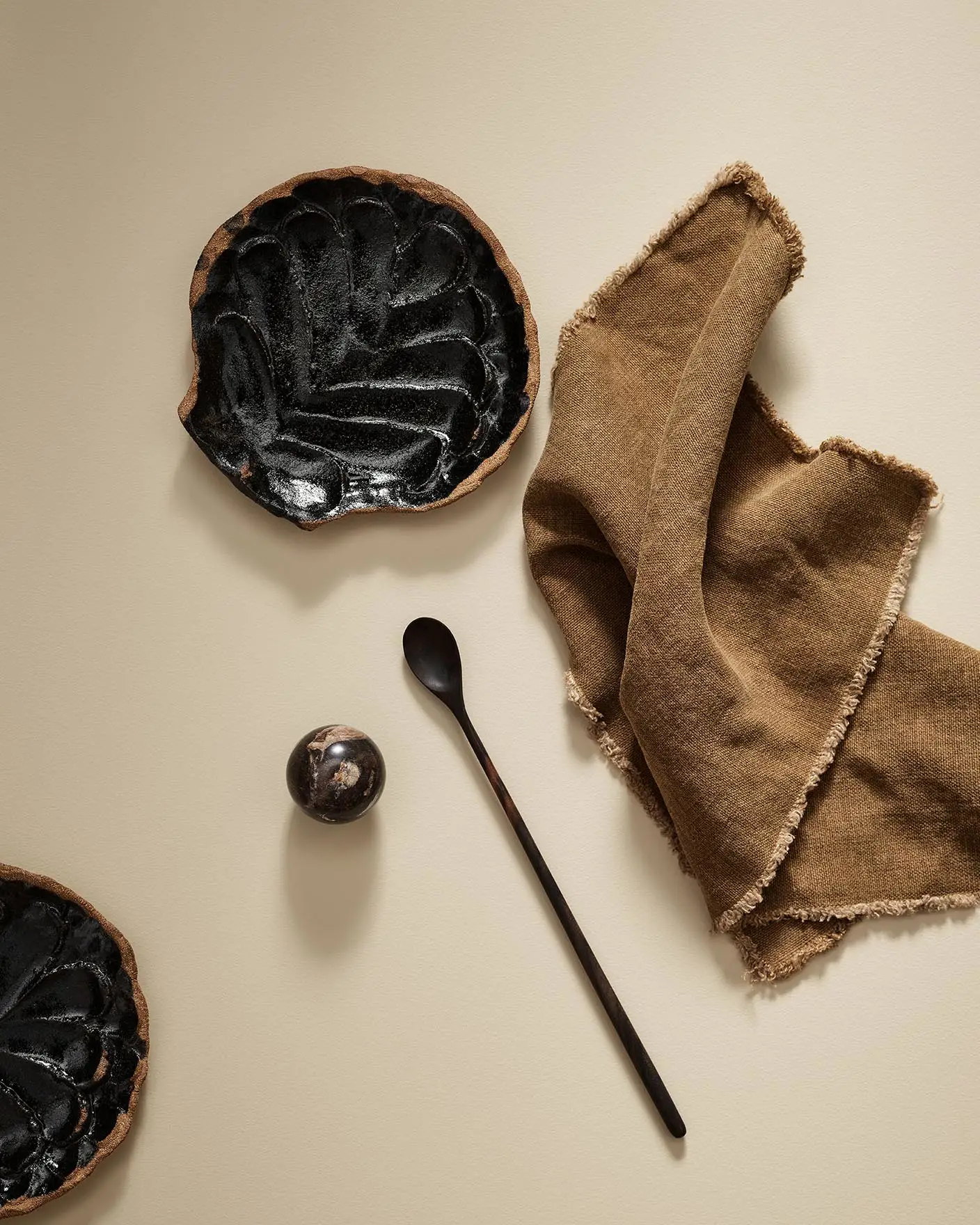 Black ceramic plate with a spoon and brown cloth on a beige surface in the colour 1303 Observe from Jotun.