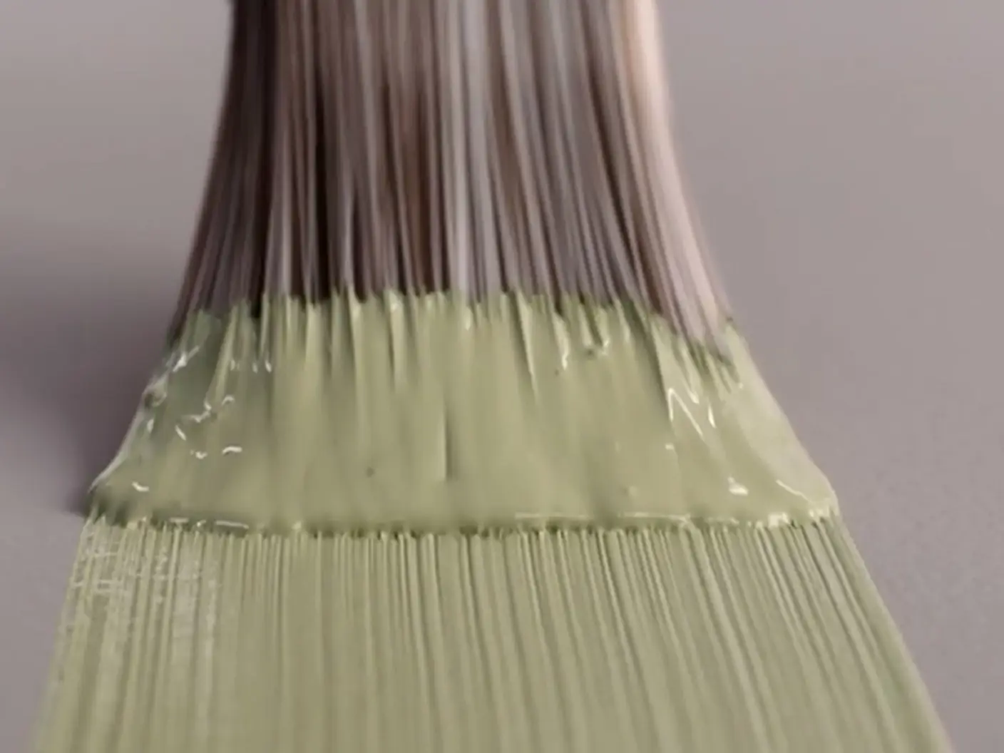 Malekost med lys grønn maling på børste, nærbilde mot grå bakgrunn